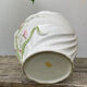 White ceramic pot cache of flower slip and old green foliage