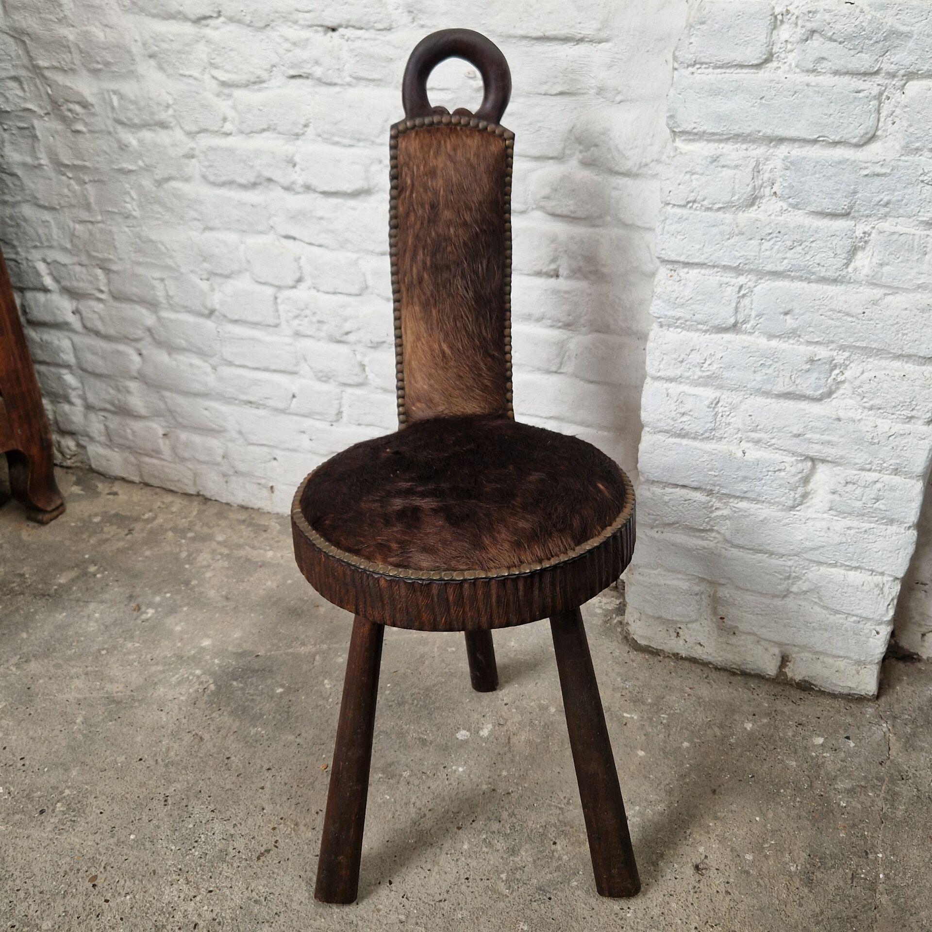 Antique tripod chair in solid wood and animal skin.