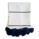 Handwoven throw with black stripes and pom-poms