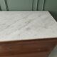 Antique solid wood chest of drawers with a white marble top.