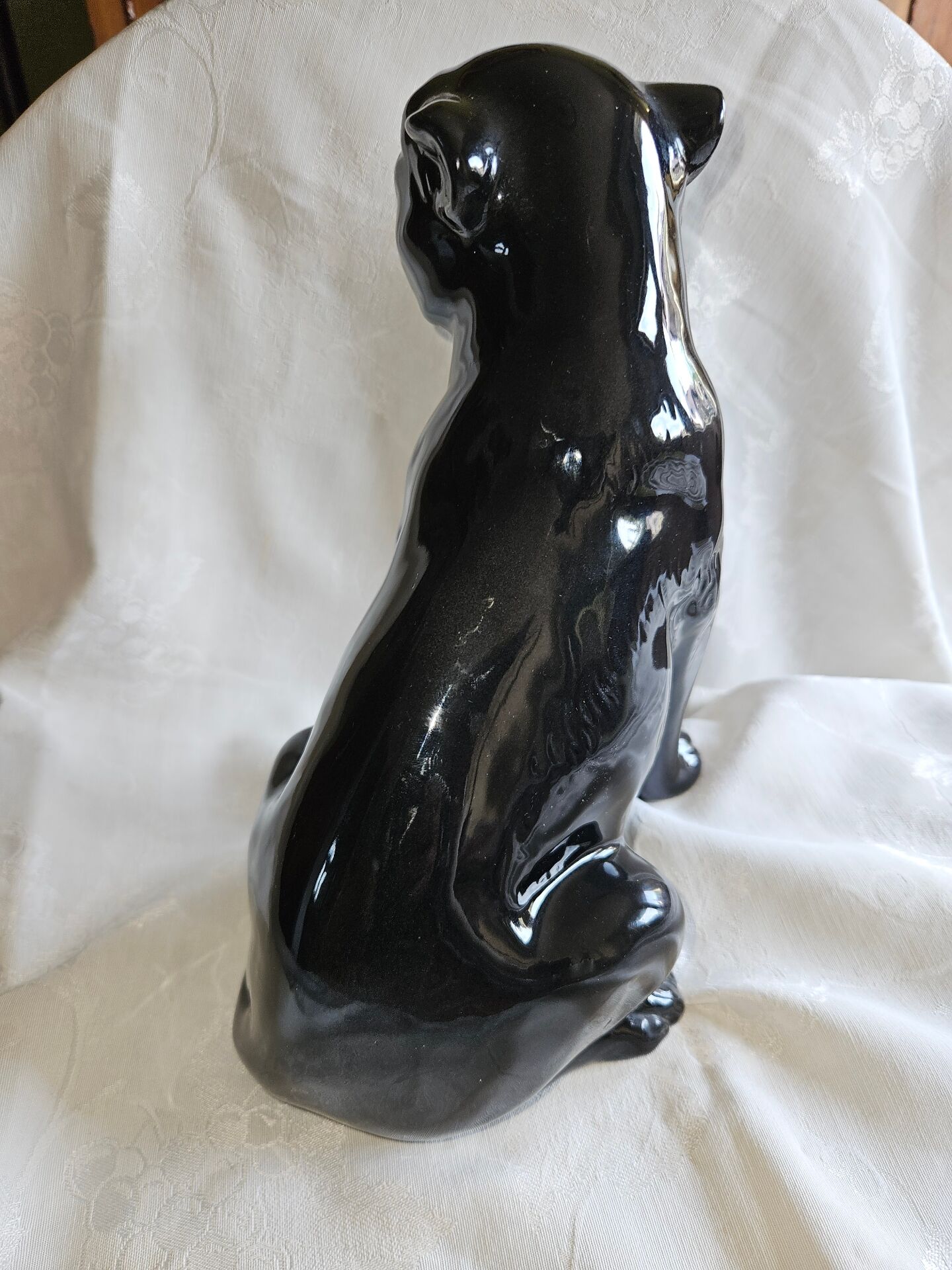 Statue of a roaring panther/leopard sitting in black glazed ceramic.