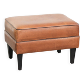 Handy sheepskin ottoman with warm colours finished with black piping