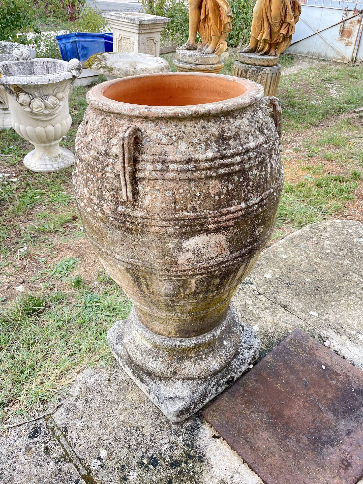 Large Cretan jar in terracotta with three handles on a stone base.