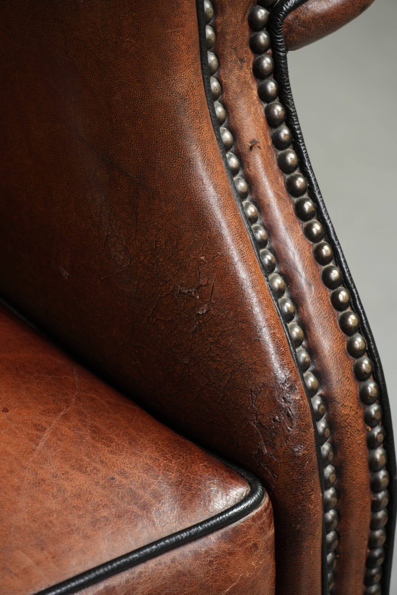 Sheepskin wingback armchair finished with black piping and a correct seat