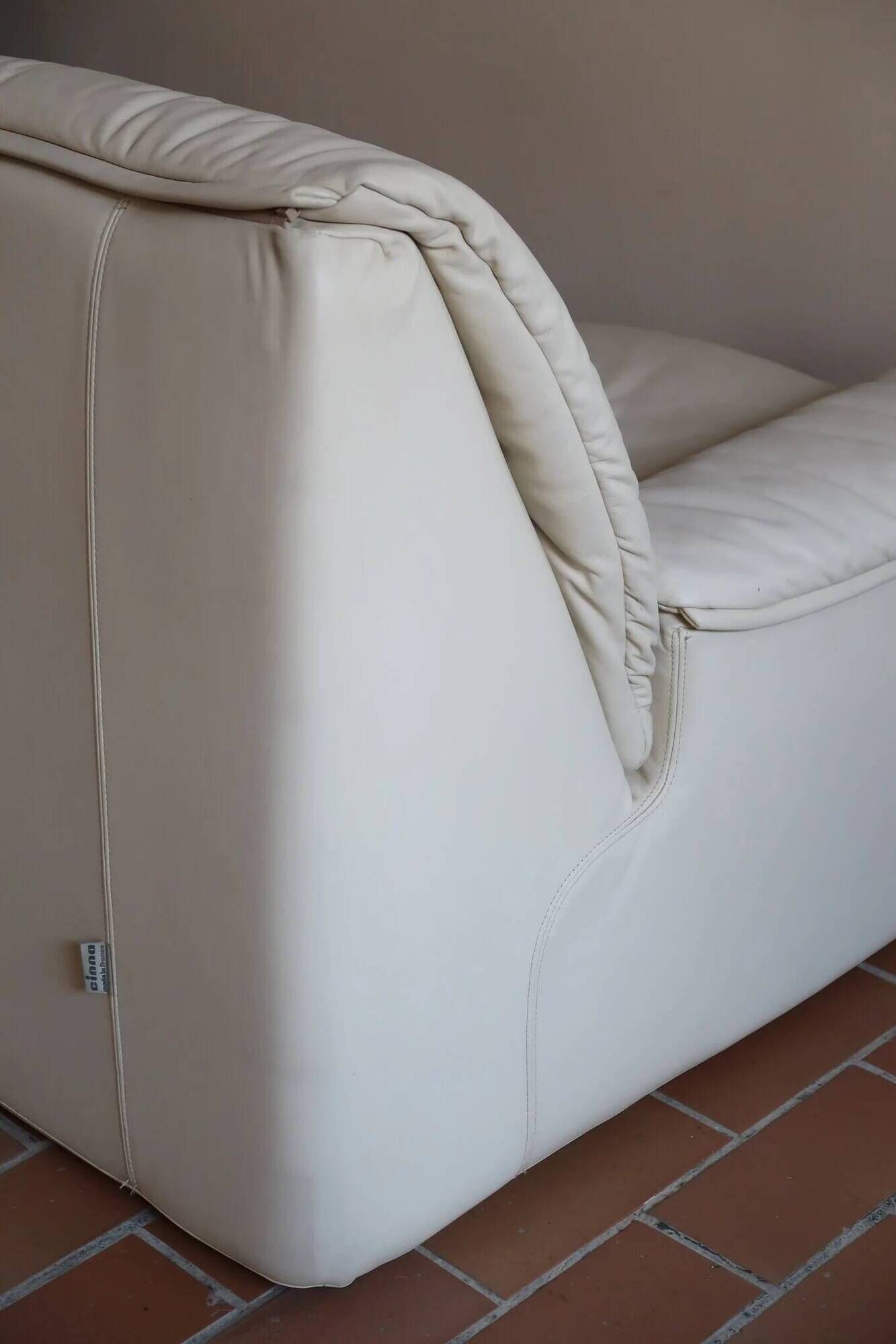 Cinna armchair in cream leather, bolstered armrests, 1970s.