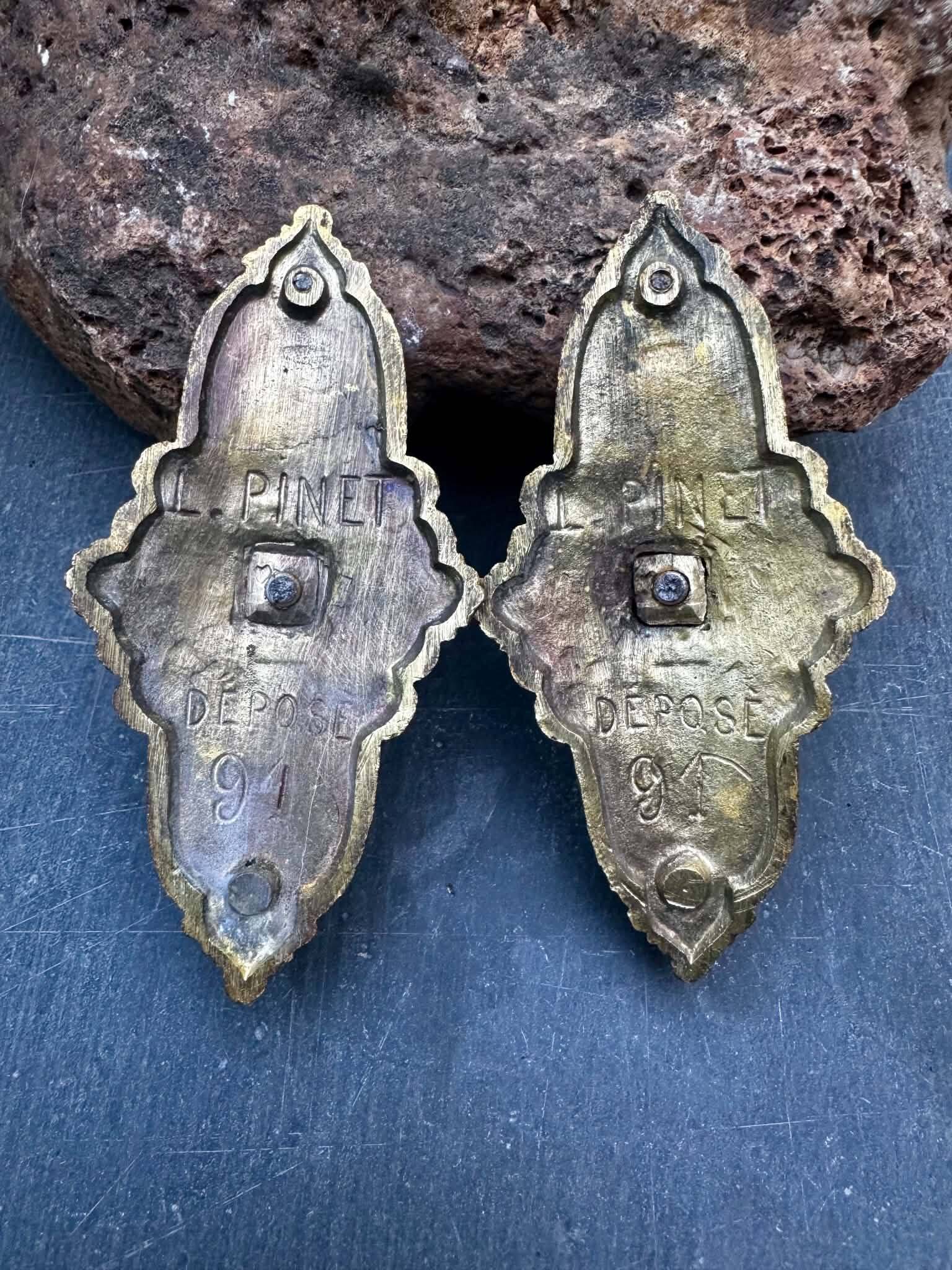 Pair of bronze wall sconces with mask, signed L. Pinet, Art Nouveau period.