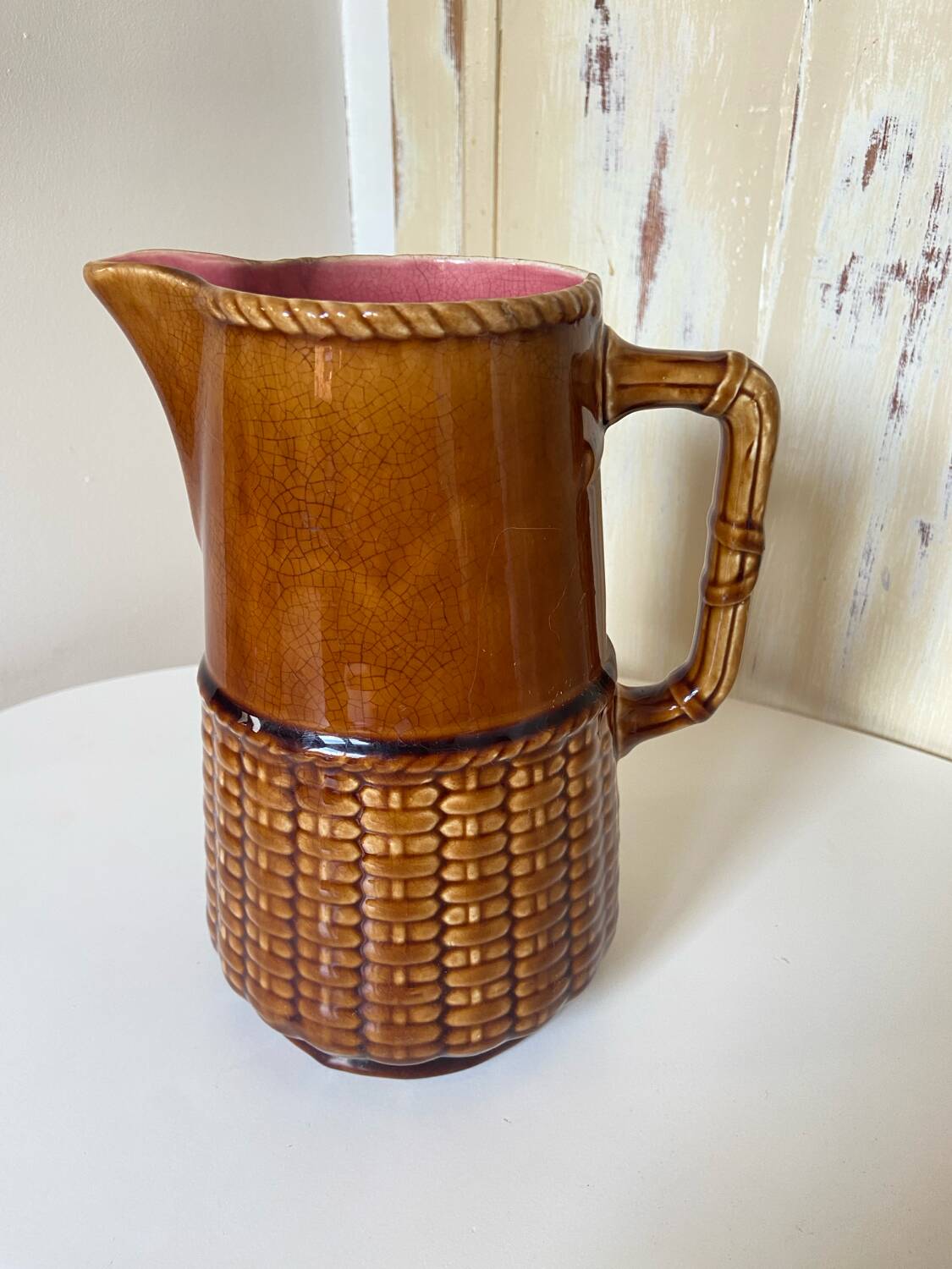 Antique vintage ceramic pitcher or jug from Sarreguemines, France. Brown with a pink interior, imitation basket.