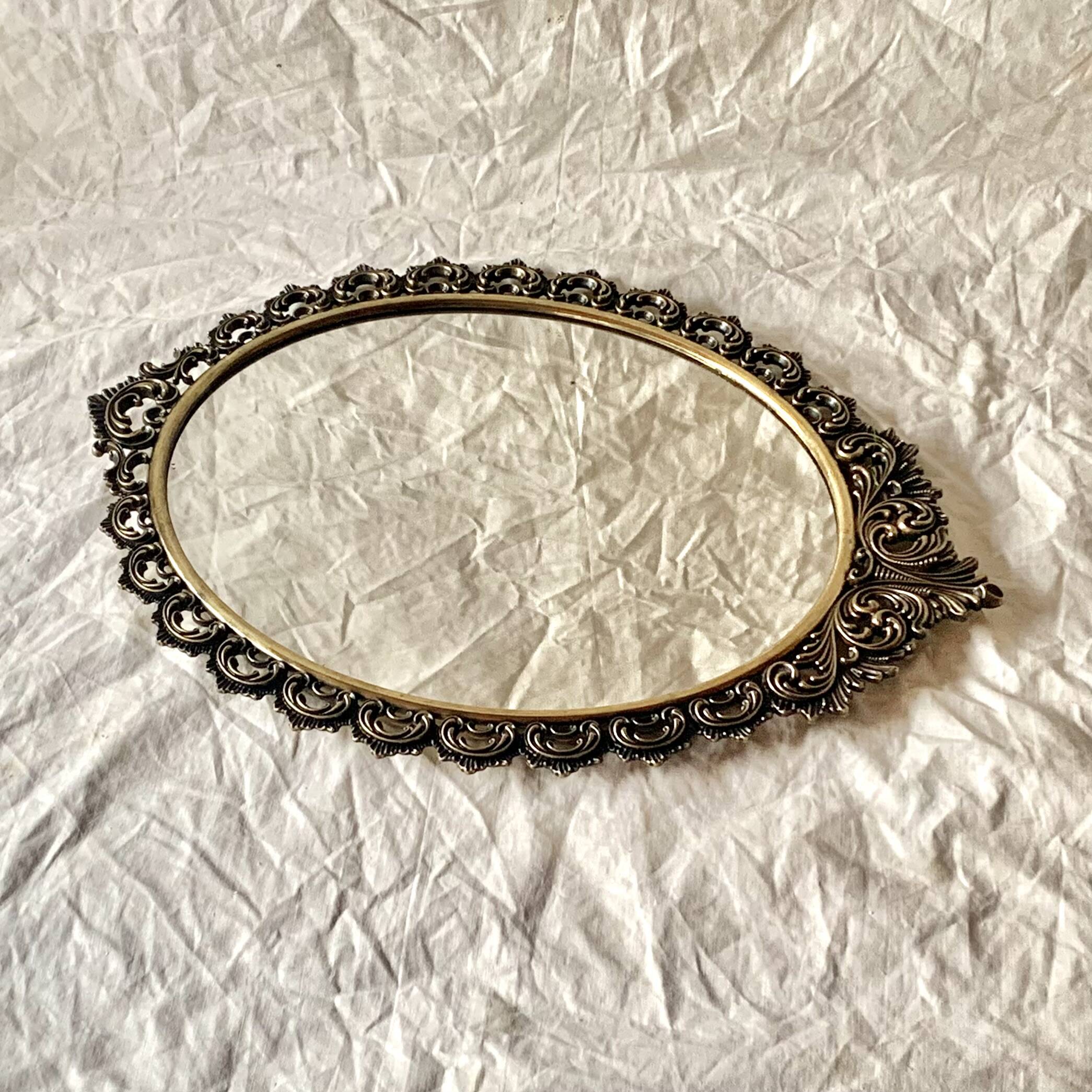 Old oval wall mirror in gilded brass