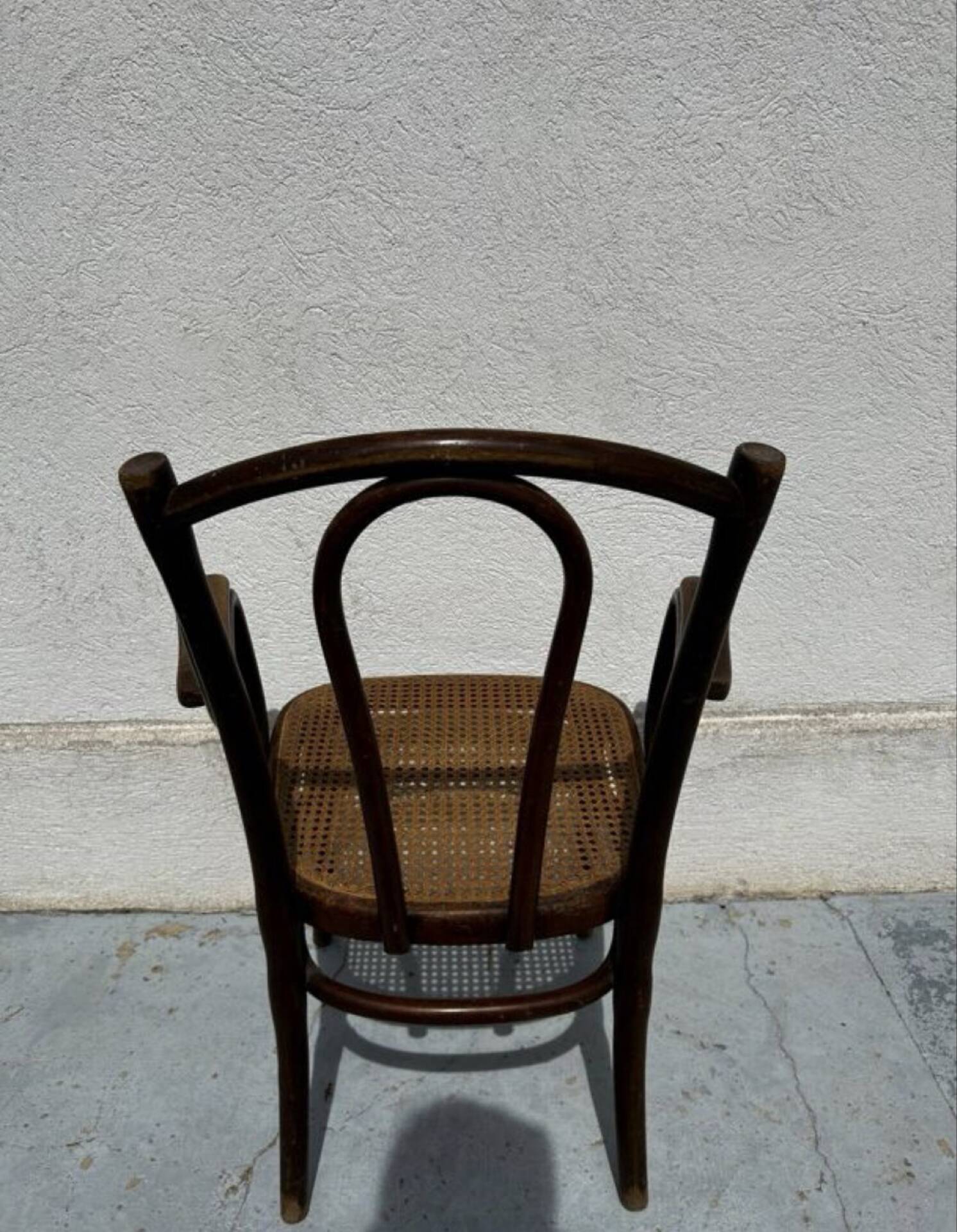 Thonet armchair stamped with curved wooden armrests and caning from the 19th century.