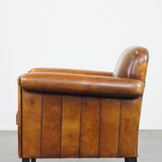 Sheepskin Art Deco design armchair with sleek finish and black piping