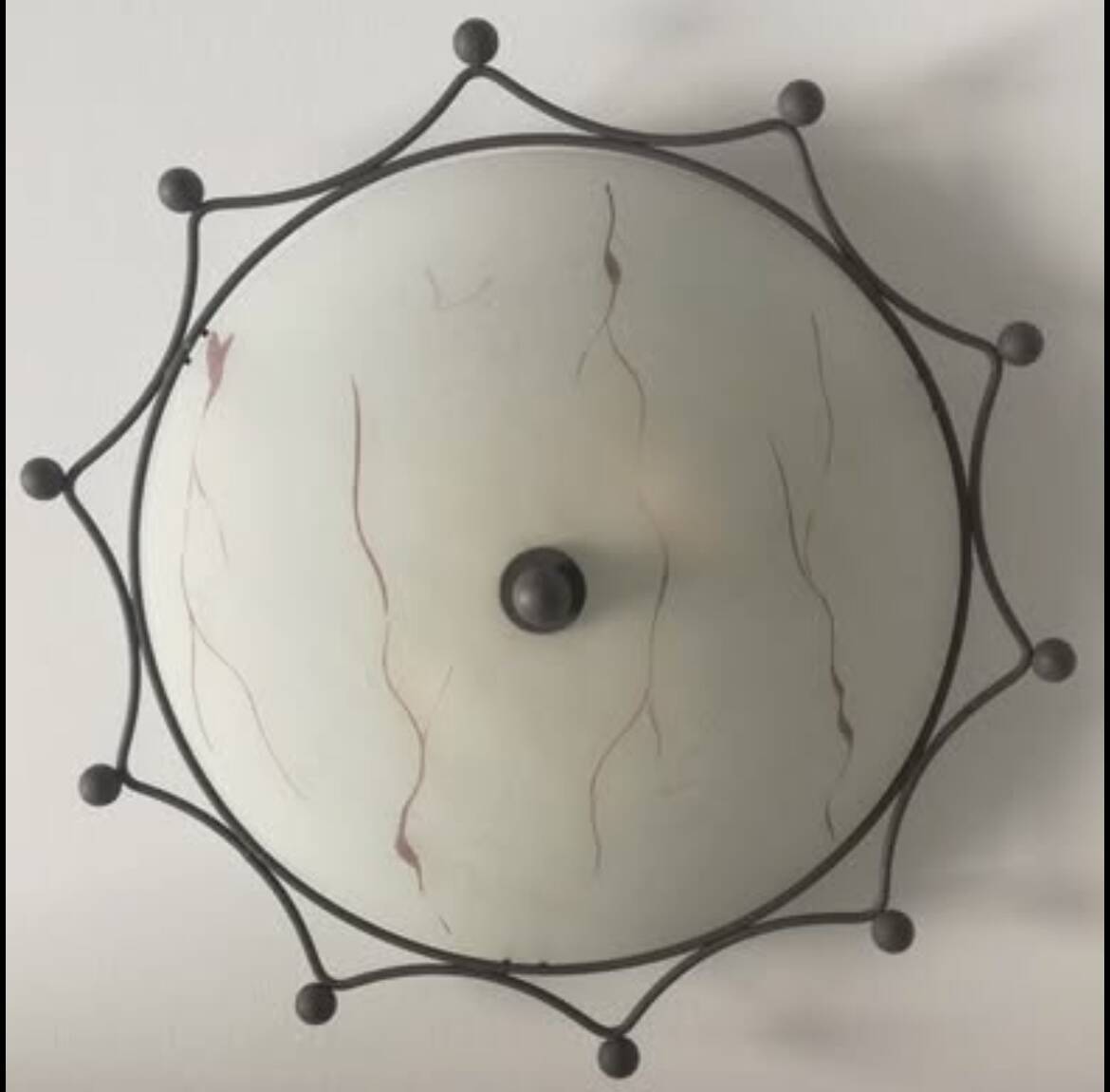 Round ceiling light with a wrought iron frame.