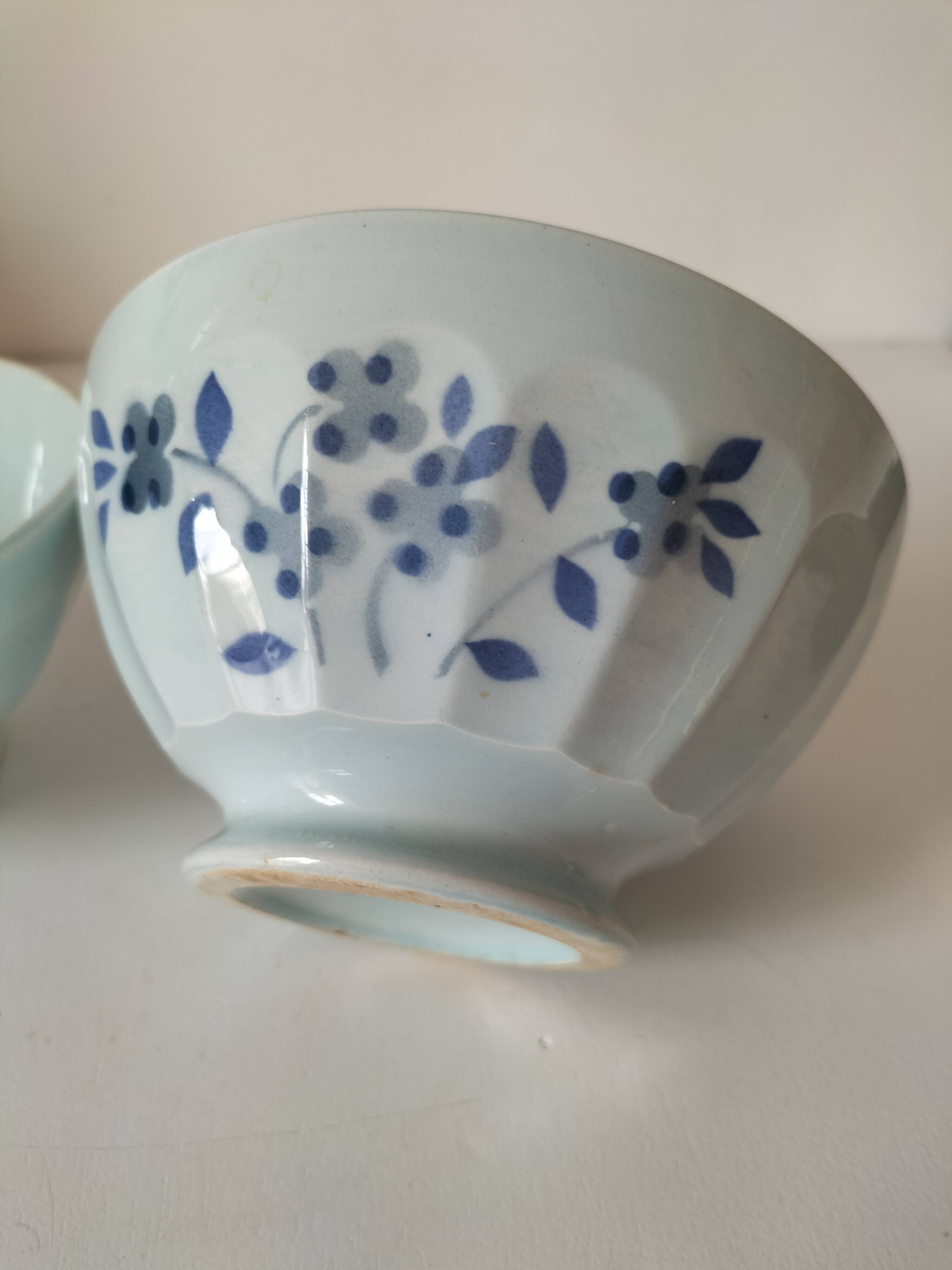 Two vintage farm bowls on a pale blue pedestal with floral decoration.