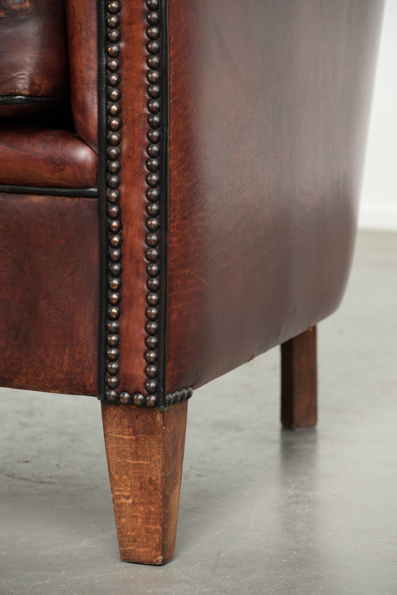 Vintage sheepskin club armchair with decorative nails and black piping