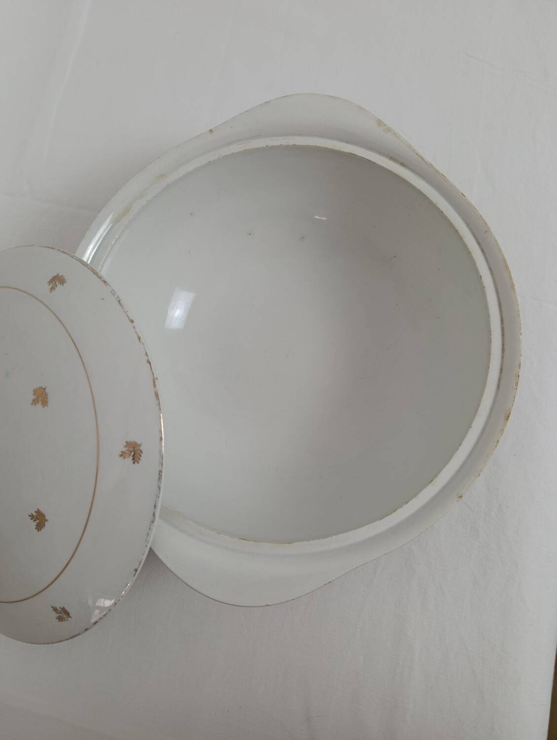 White earthenware soup tureen with a golden pattern.