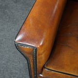 Art deco armchair in sheepskin with black piping and decorative nails