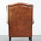 Large sheepskin wingback chair with black piping and decorative nails