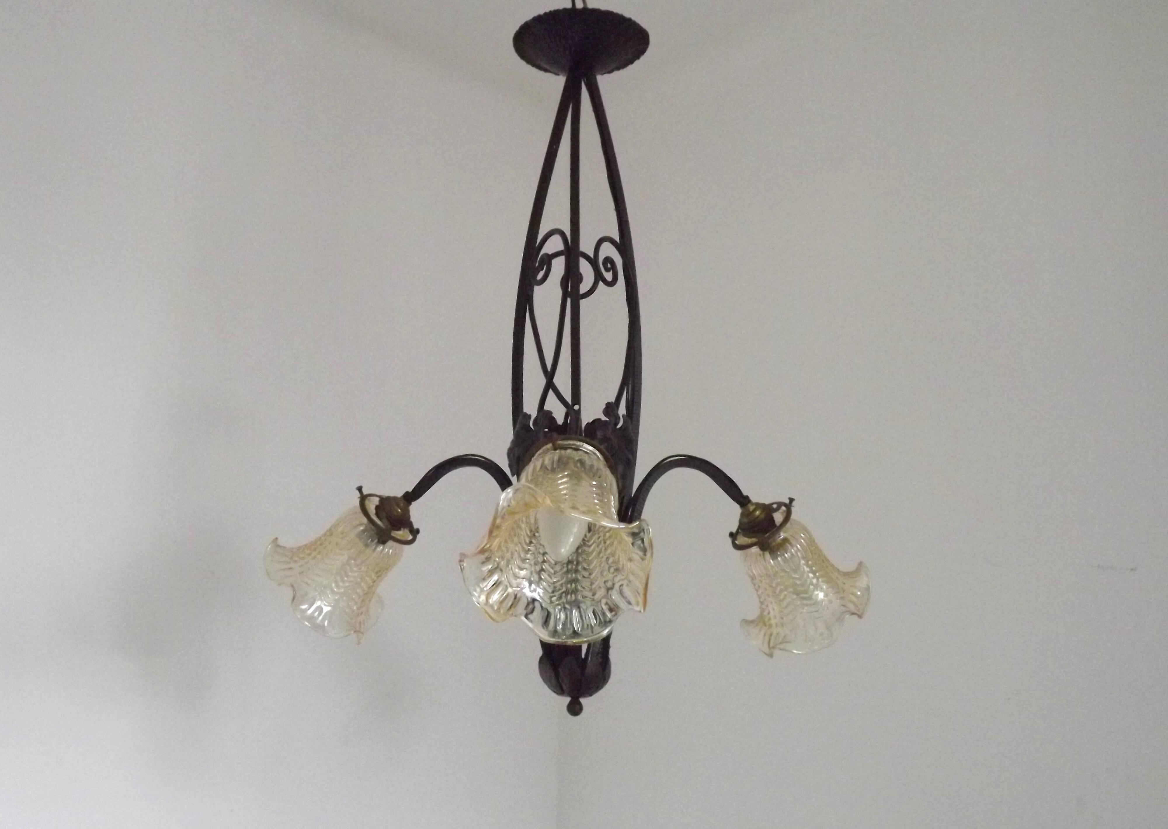 French Art Nouveau leaf detail iron three-light chandelier with amber glass shades.