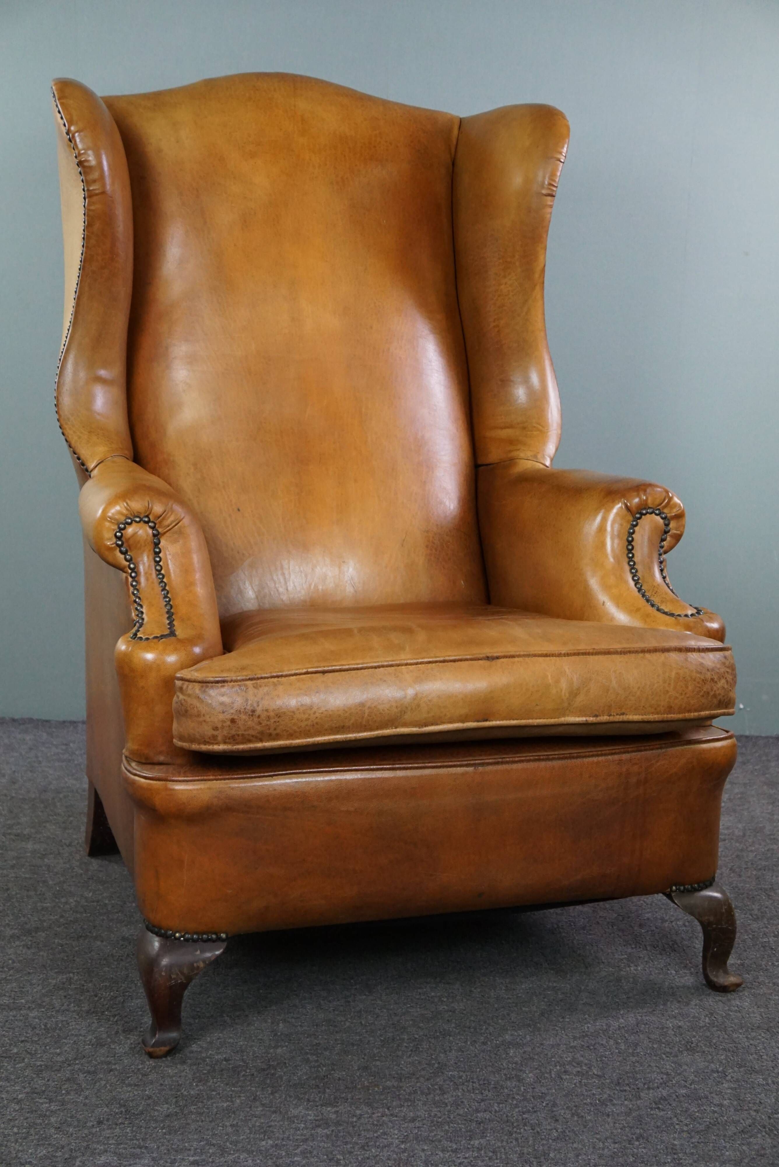 Old wingback armchair made of sheep leather in a correct condition