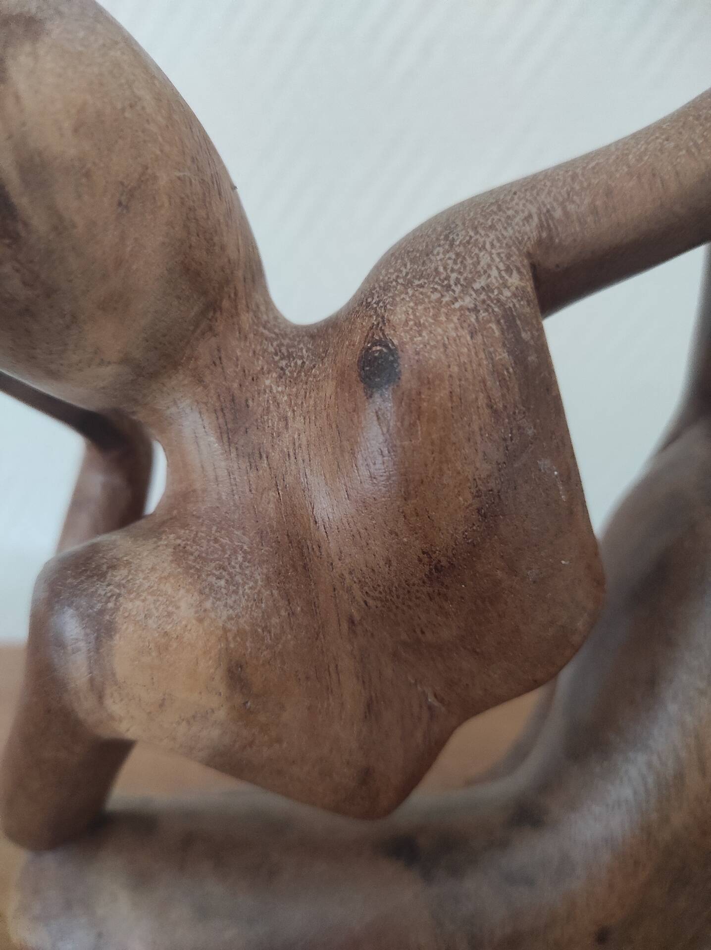Wooden sculpted statuette of a woman in a pensive pose.