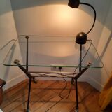 Vintage table with thick glass top and black steel legs with casters.