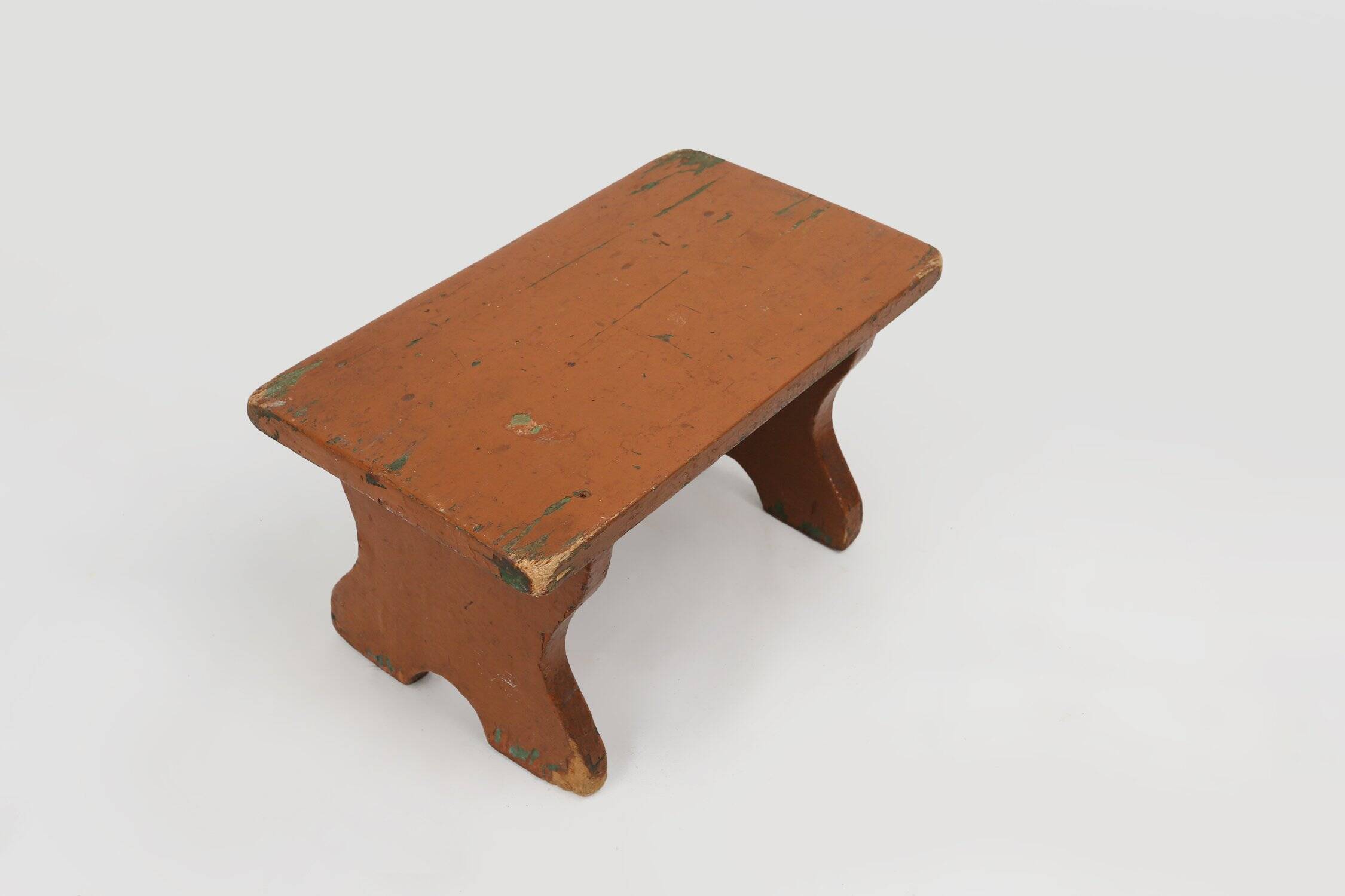 Tabouret bas rustique français en bois peint en terre cuite, années 1890.