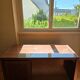 Large wooden desk with a glass top and a wheeled drawer unit.
