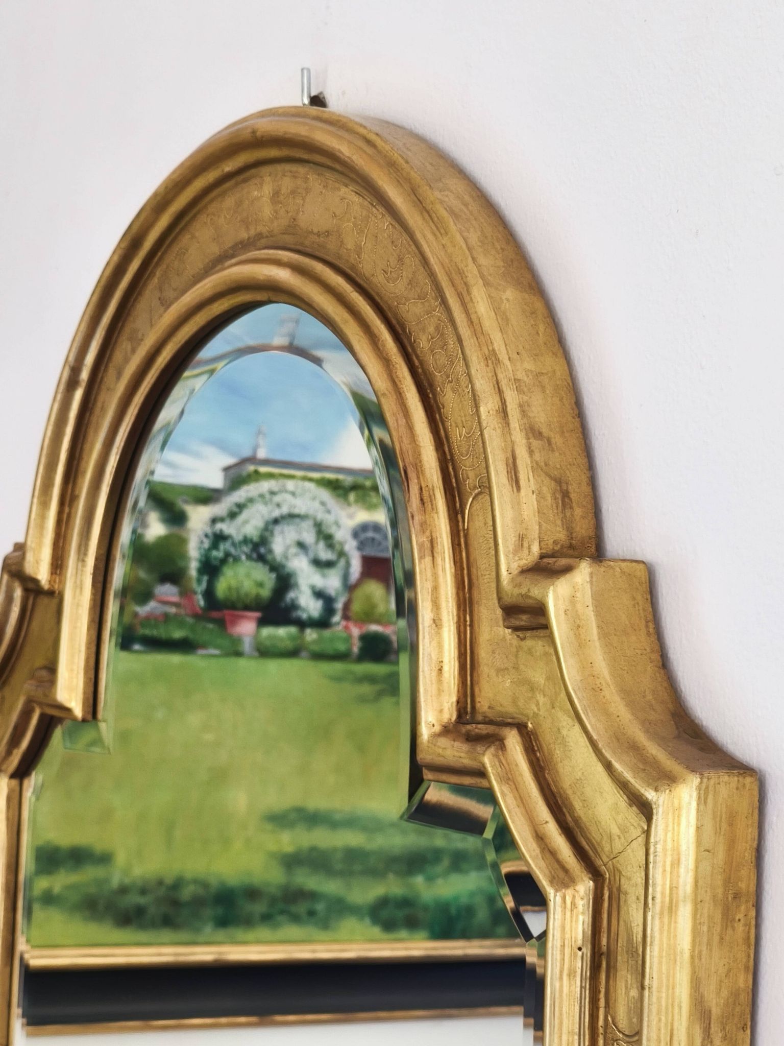 Florentine arched mirror in gilded wood with gold leaf.
