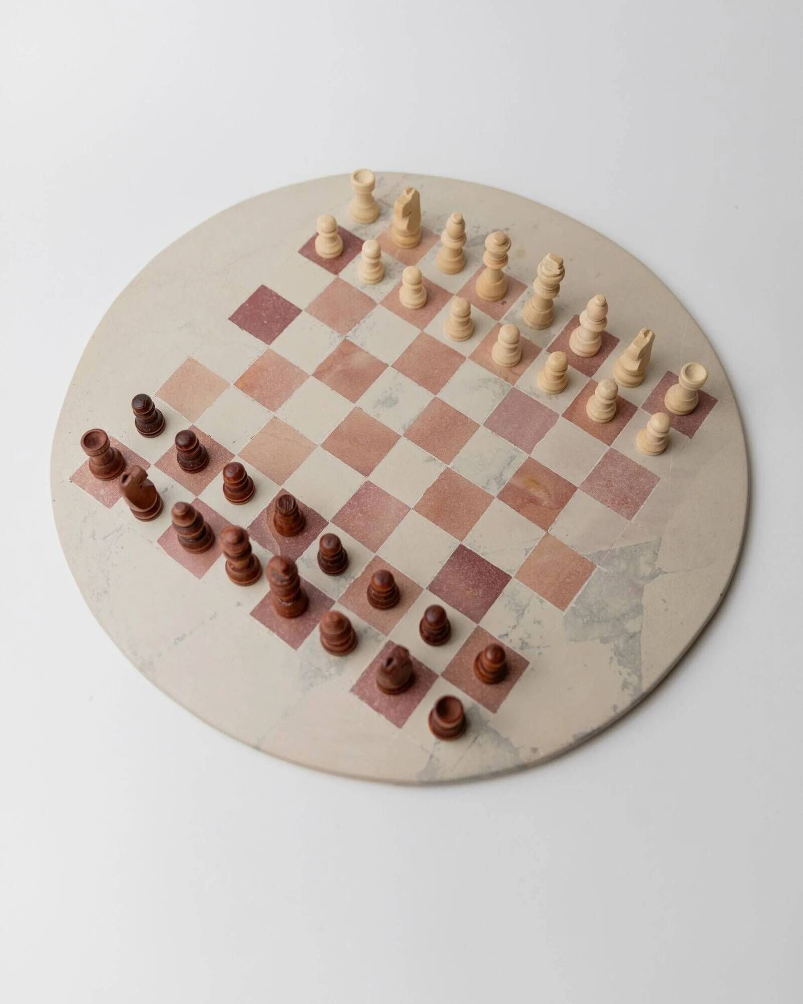 Vintage 1980s round chess set in marble, with a beige and pink marble board and wooden pieces.