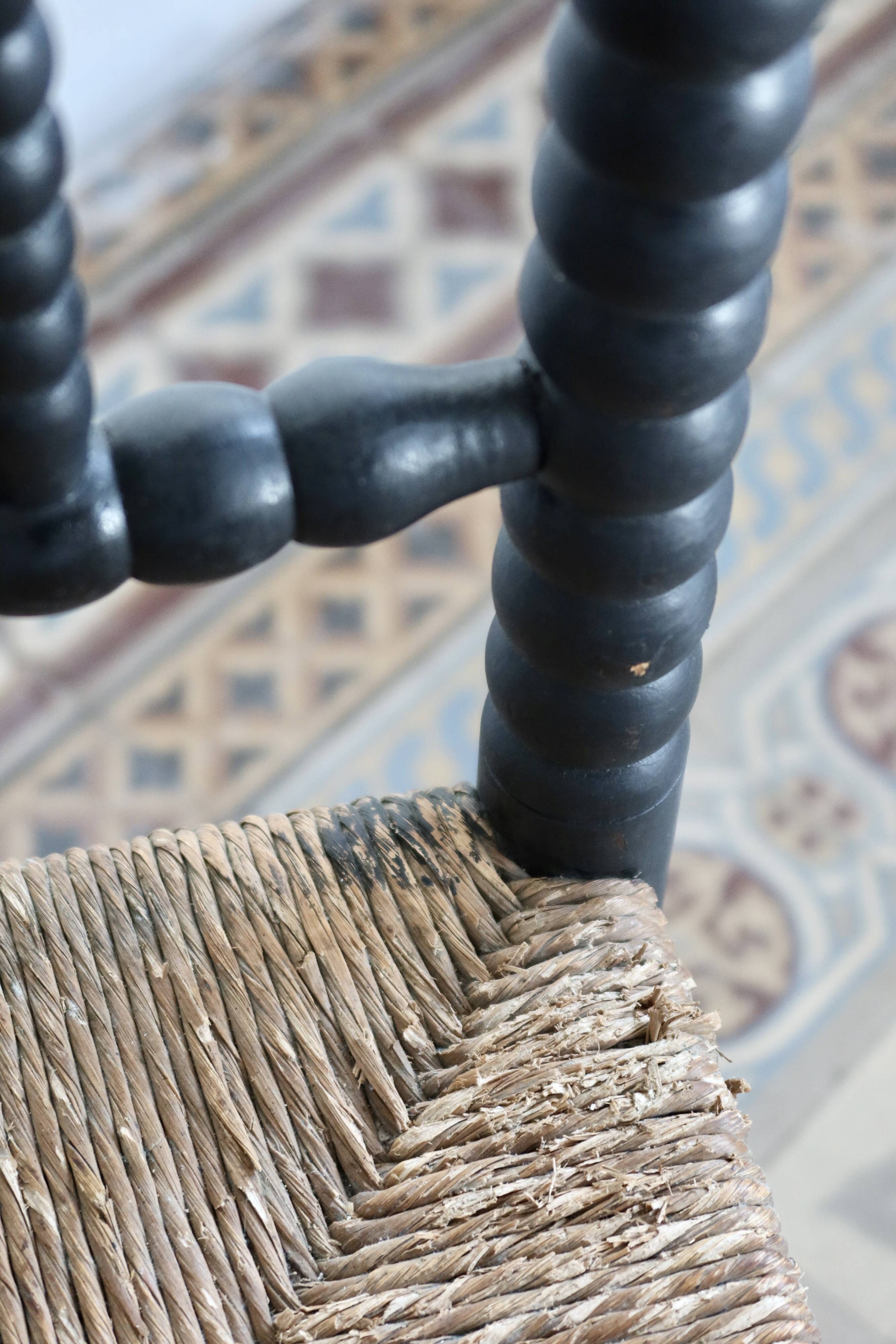 Antique black turned wood corner chair with a straw seat.