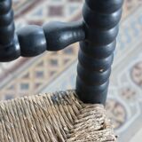 Antique black turned wood corner chair with a straw seat.