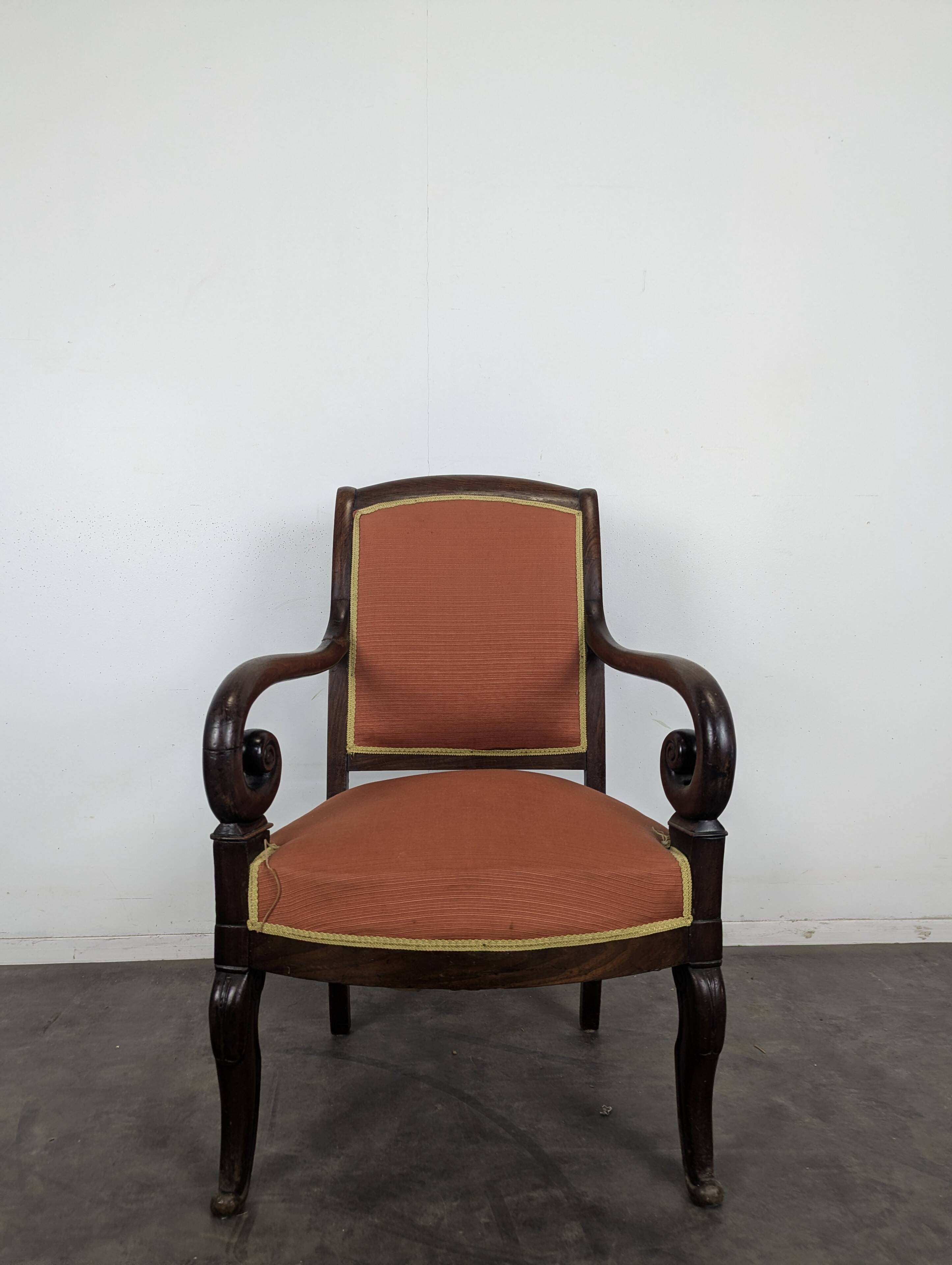 Restoration armchair in mahogany with cross arms and orange fabric.