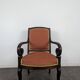 Restoration armchair in mahogany with cross arms and orange fabric.