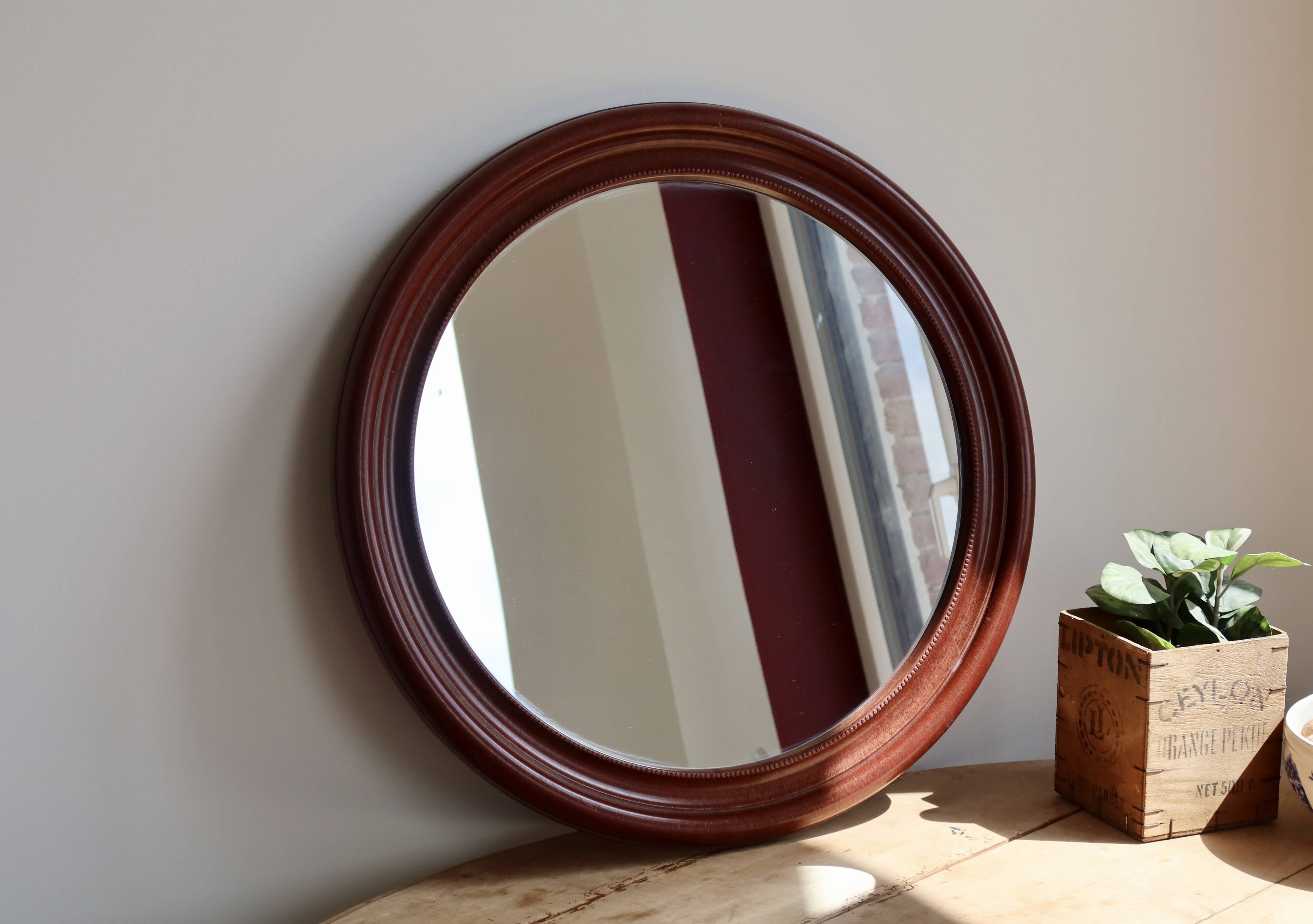 Round vintage mirror with mahogany wood effect frame.