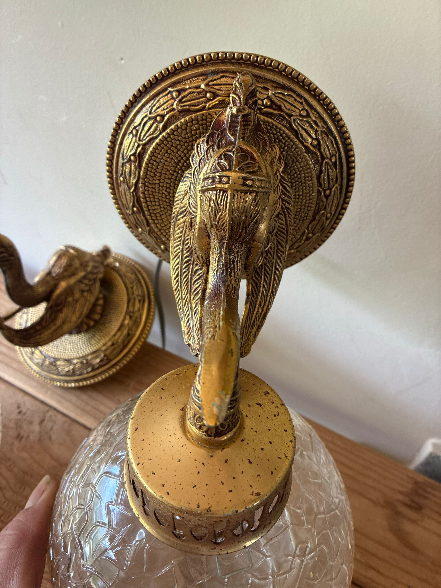 Pair of vintage wall sconces with golden metal swan heads and glass.