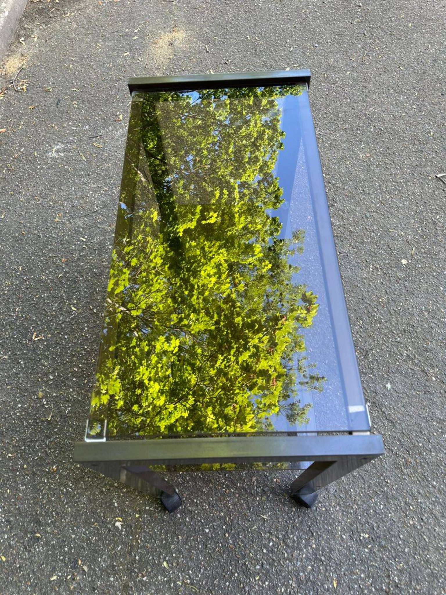 Vintage 1970s rolling bar cart made of metal and smoked glass.