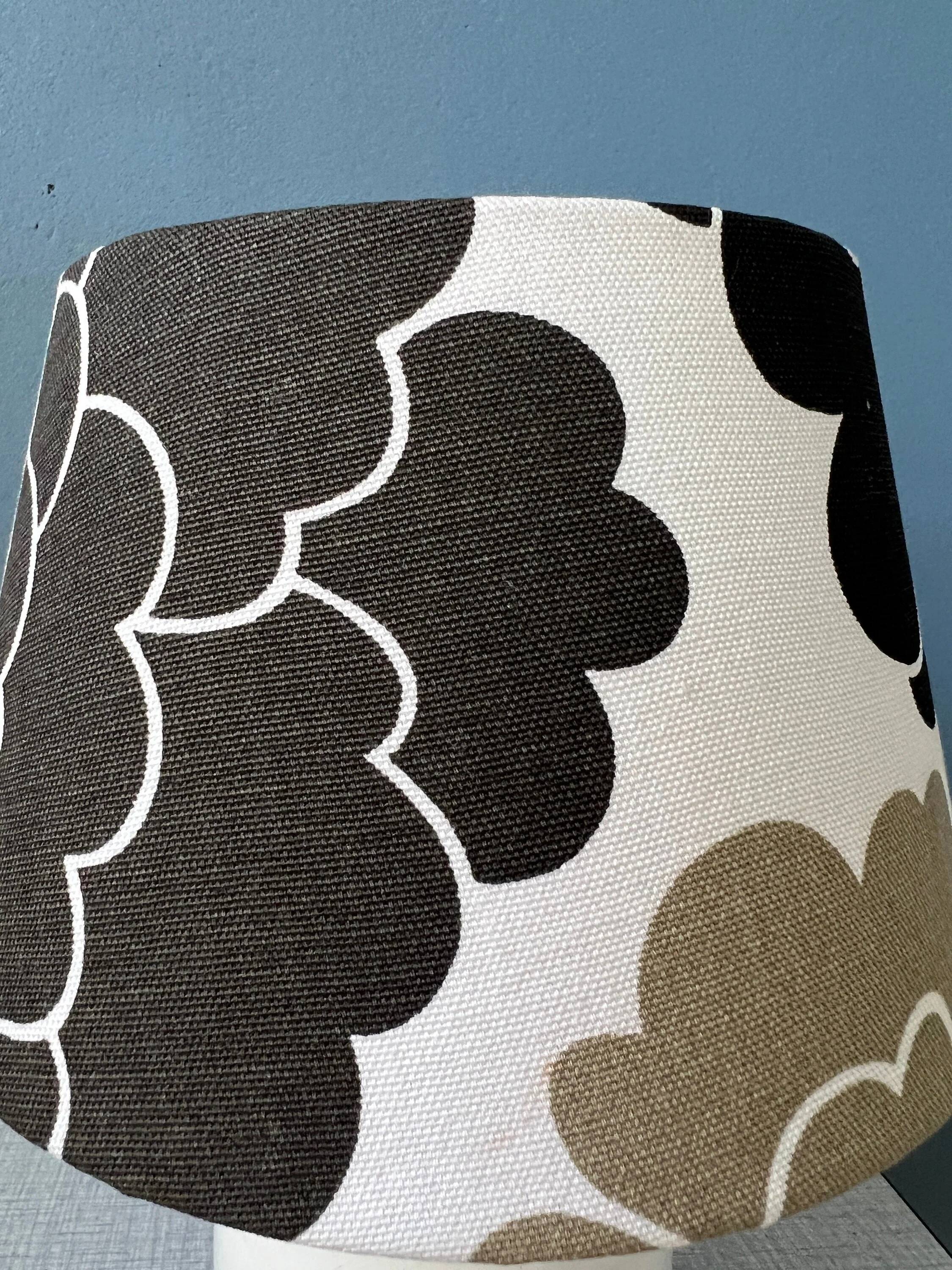 Small Space Age table lamp with a porcelain base and black and white flower shade.
