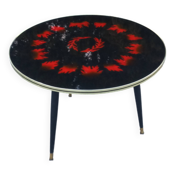 Vintage coffee table with glass top and tripod legs in blackened wood from the 1960s.