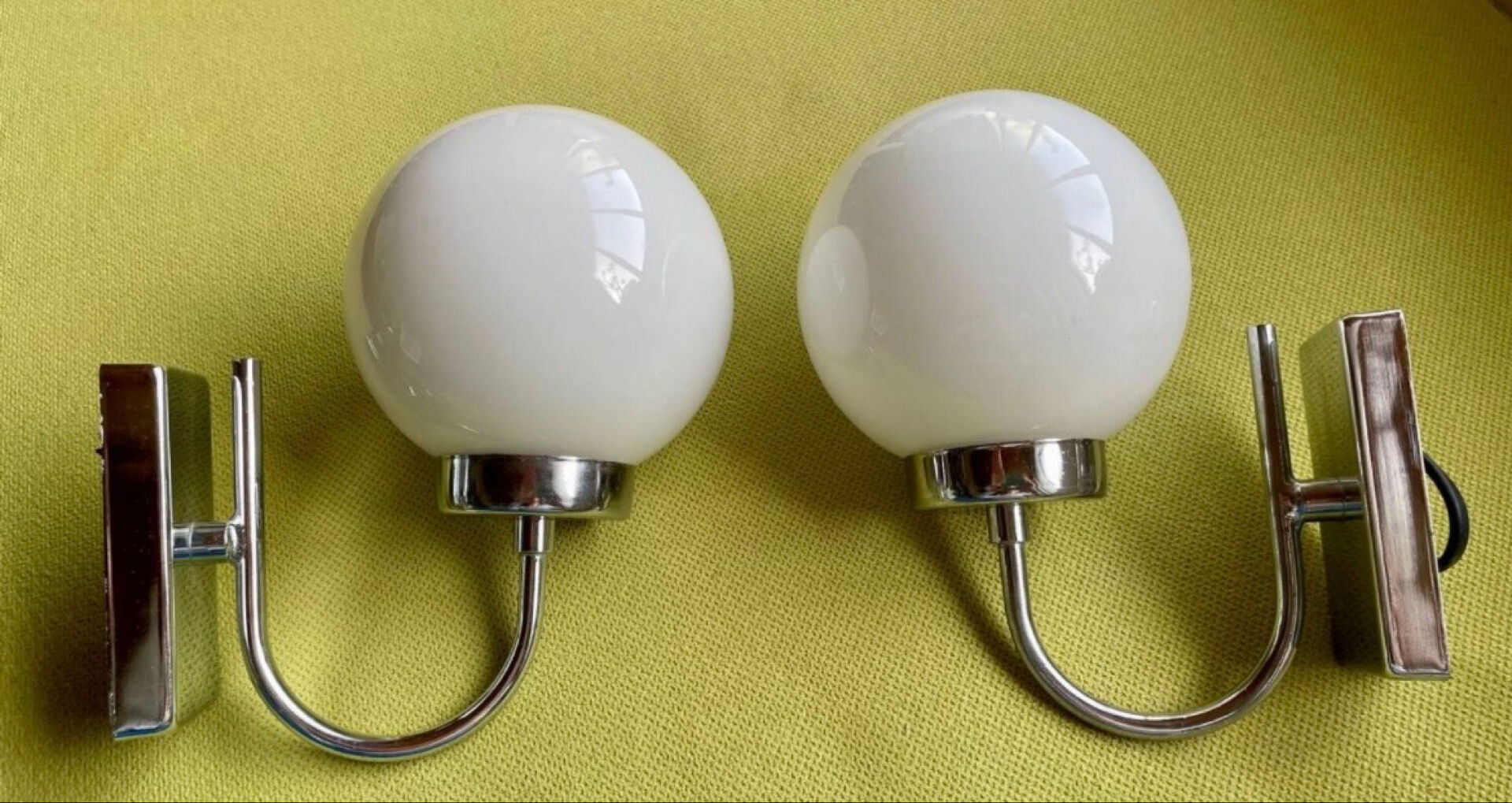 Pair of chrome metal wall lights with white glass globe.