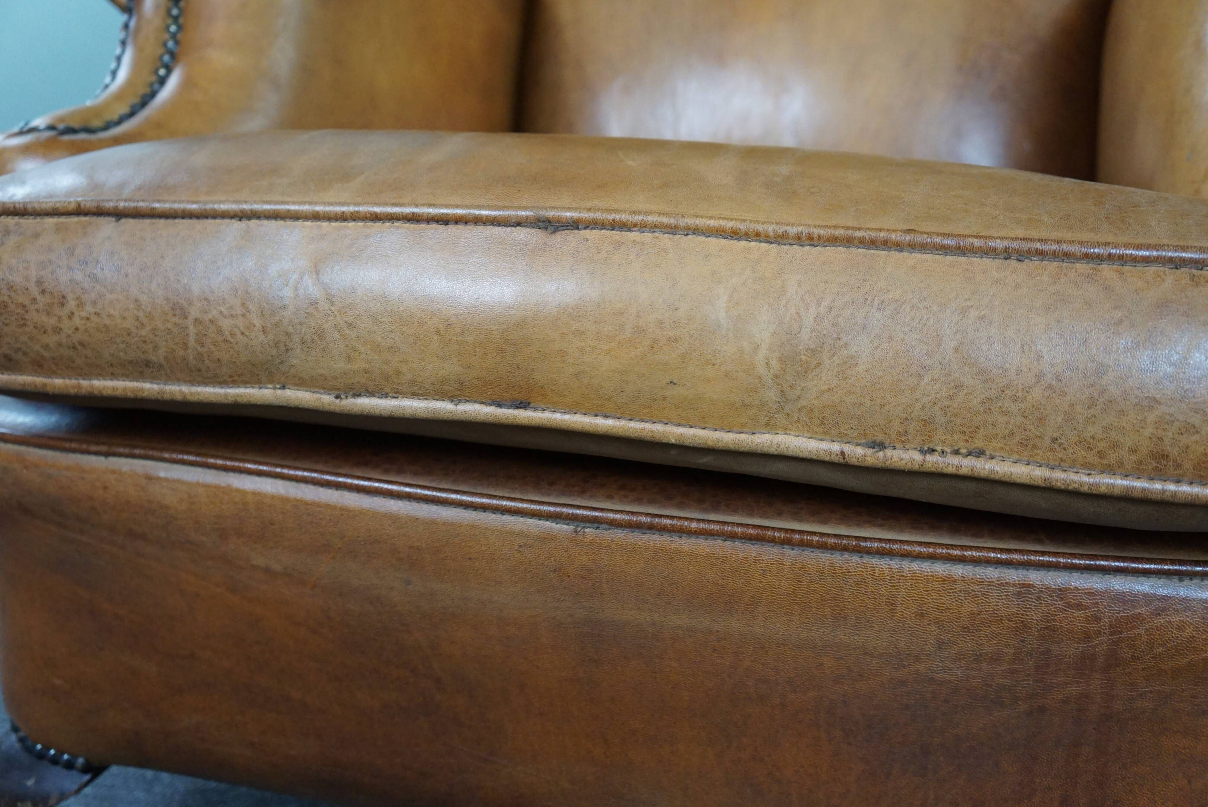 Old wingback armchair made of sheep leather in a correct condition