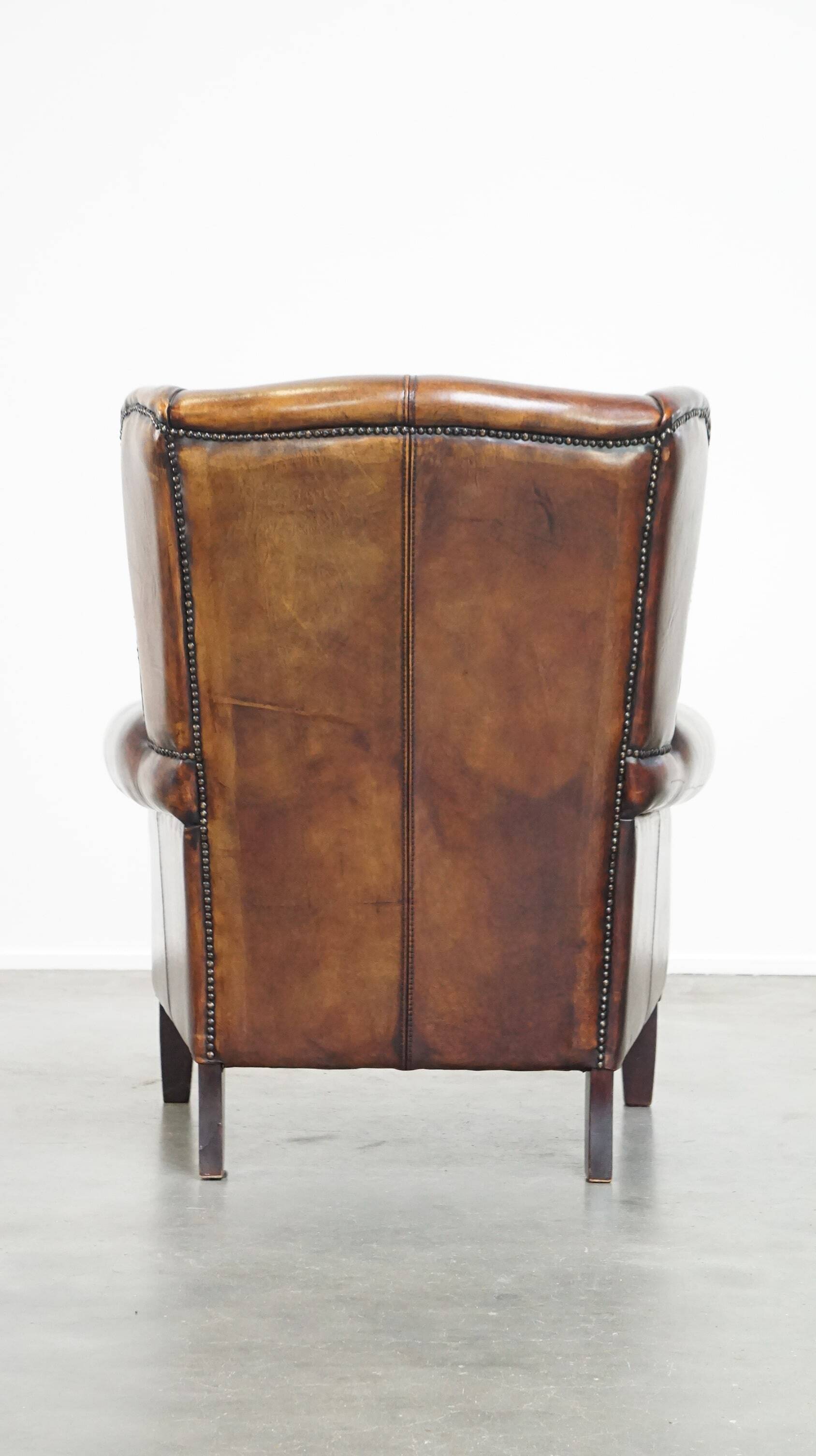 Fauteuil à oreilles confortable et bien entretenu en cuir de mouton