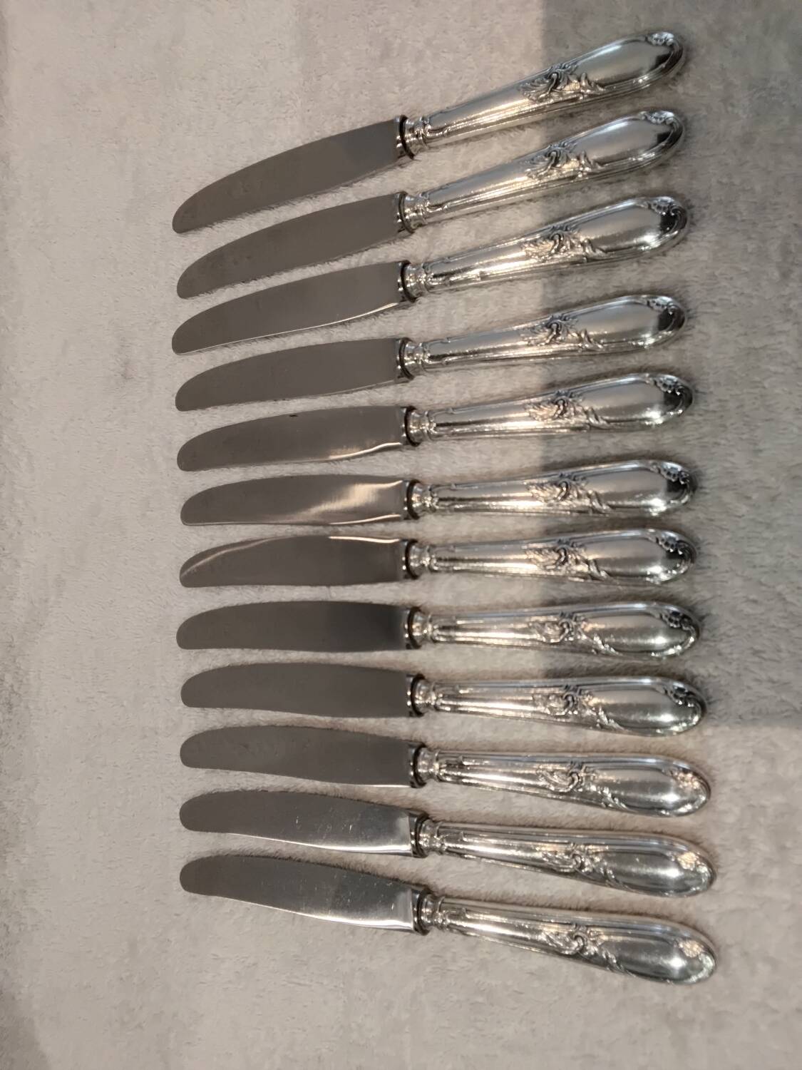 12 silver-plated metal dessert knives with rocaille ribbon decoration, 21.4 cm