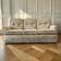 Vintage beige three-seater sofa with floral pattern and fringes.