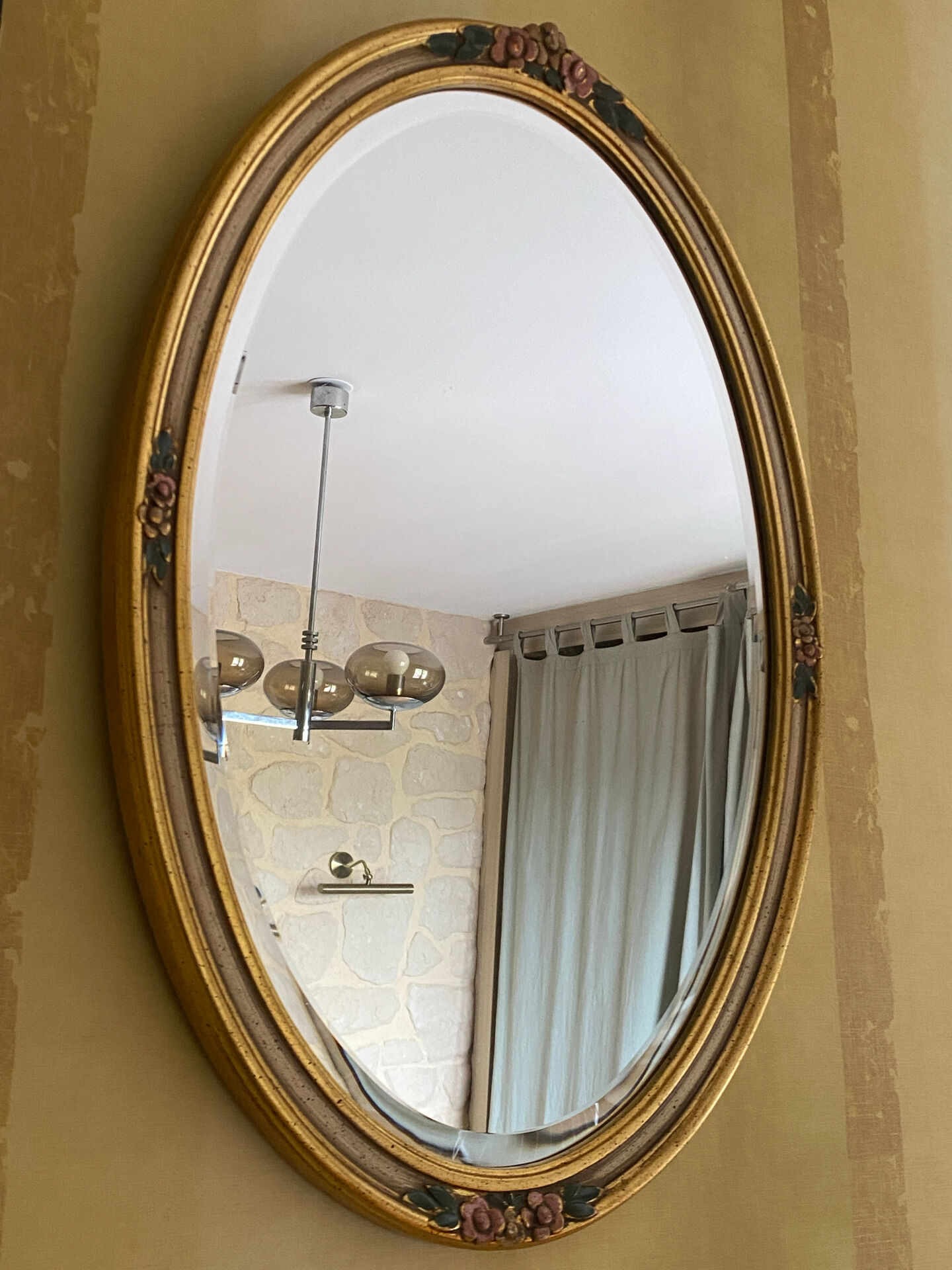 Oval wooden frame with floral decoration in gold.