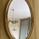 Oval wooden frame with floral decoration in gold.