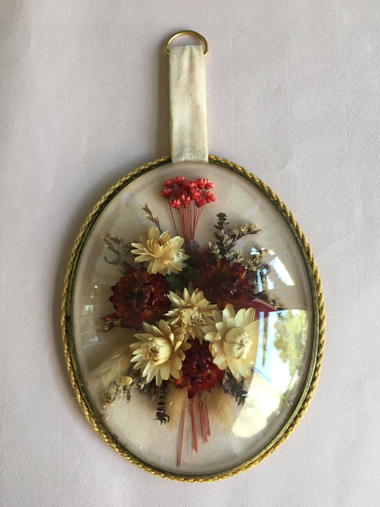Old medallion frame of dried flowers of oval shape. To hang with velvet stripe.
