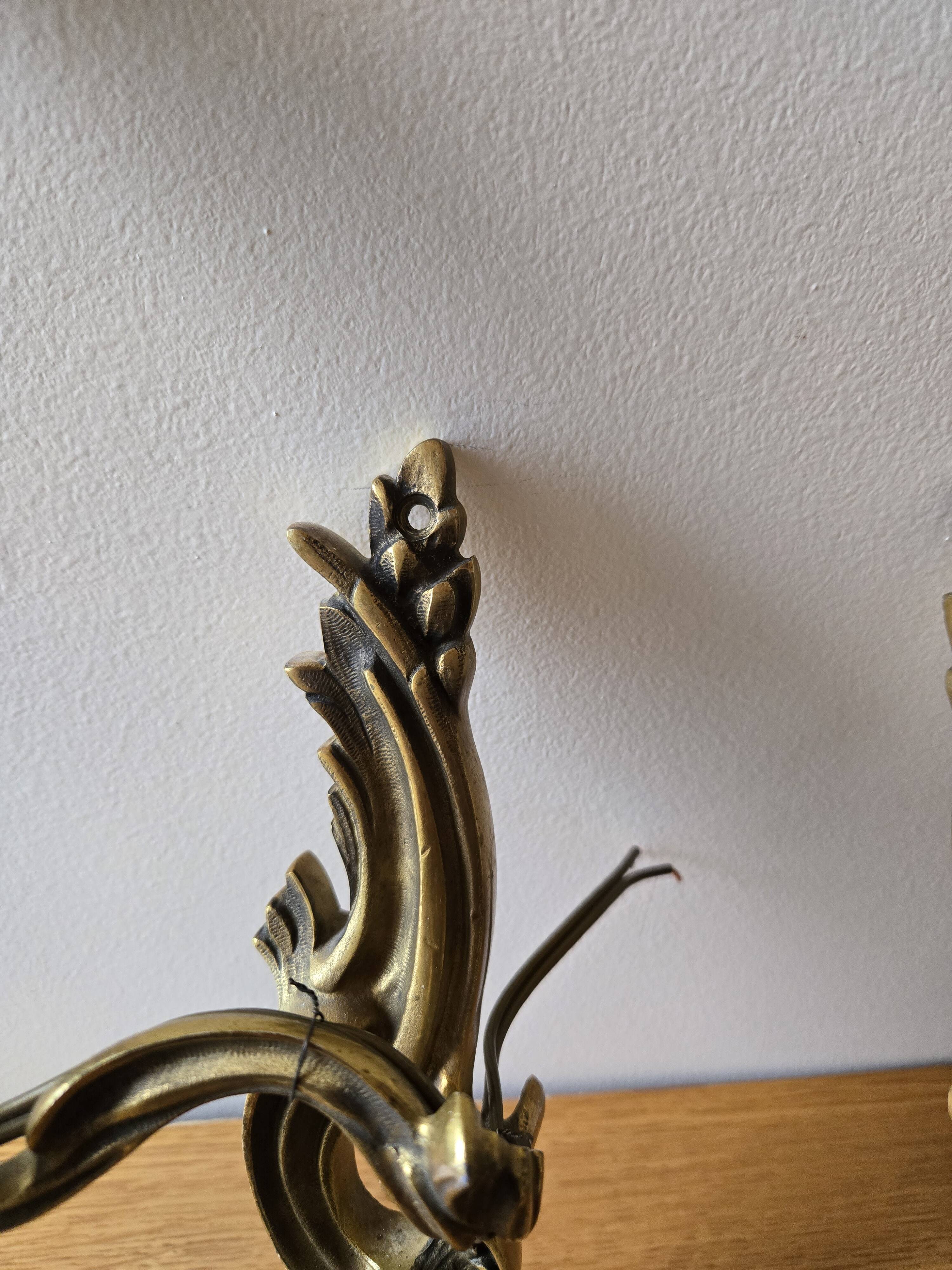 Pair of symmetrical gold wall sconces in baroque style made of bronze.
