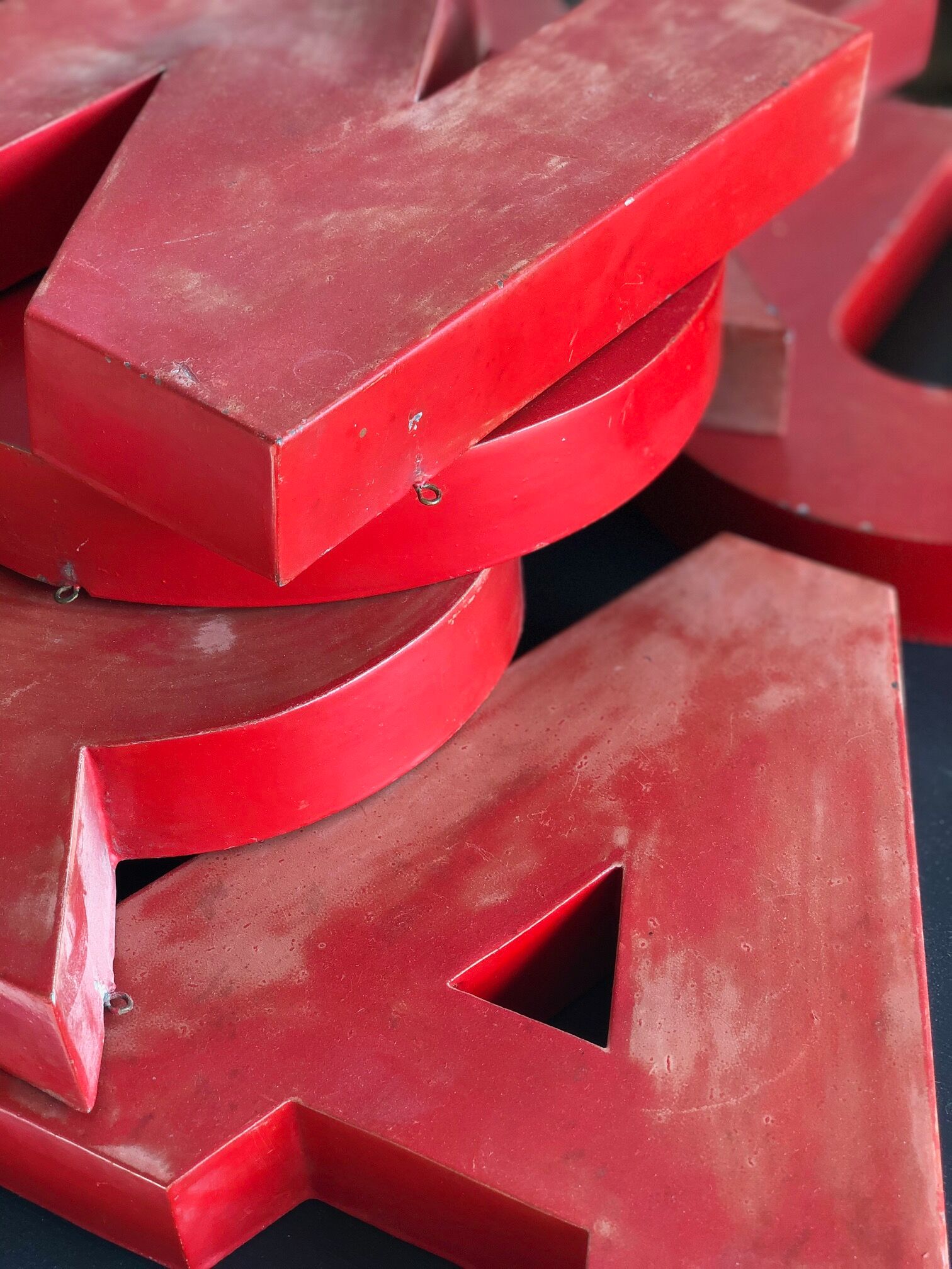 Lettres d'enseigne en zinc rouge formant le mot JOURNAUX