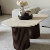 Oval coffee table in travertine and fluted wood.