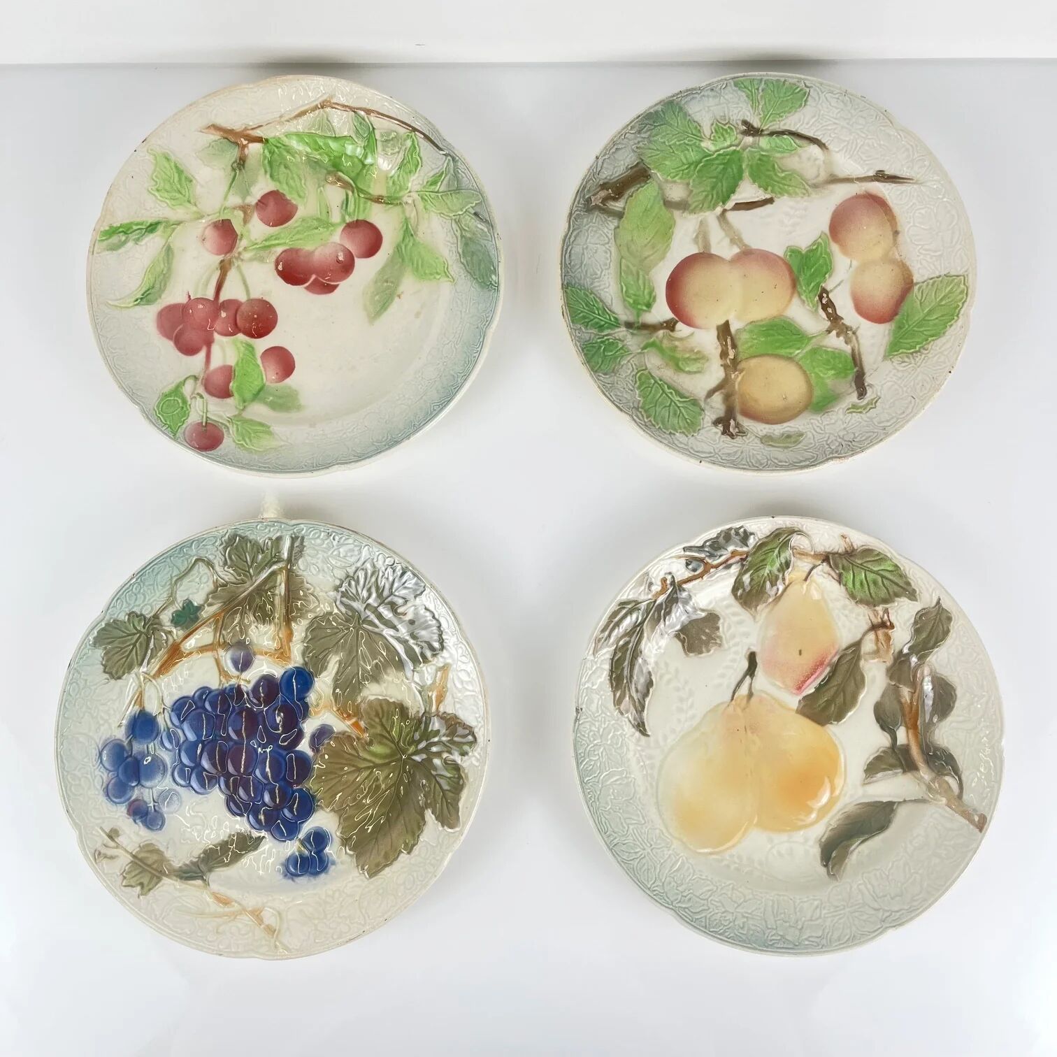 Set of 4 plates KG St Clément barbotine fruit (cherry, mirabelle, grape, pear), late 19th-early 20th century.