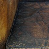 Fauteuil ancien en cuir de mouton sur roulettes et patiné